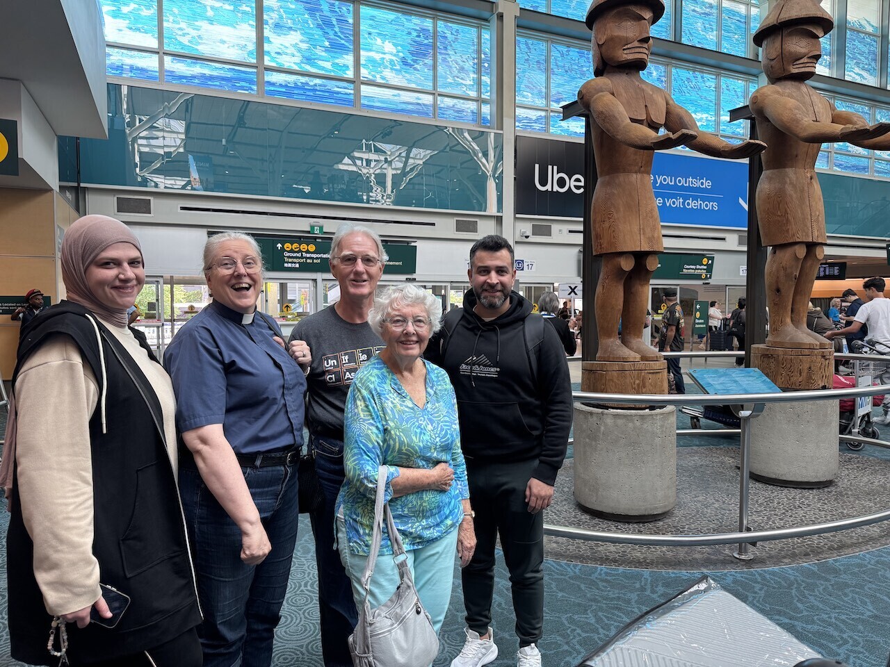 Refugee couple with Refugee Committee members at YVR 2025